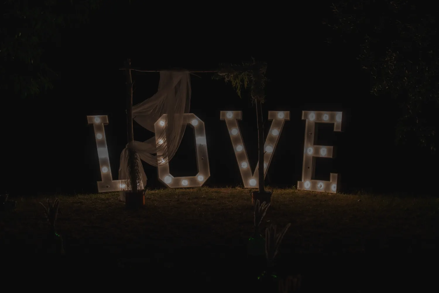 Illuminated LOVE letters in the garden at night.