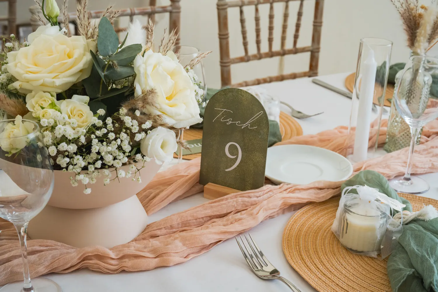 Table number, floral arrangement and candles on the wedding table.